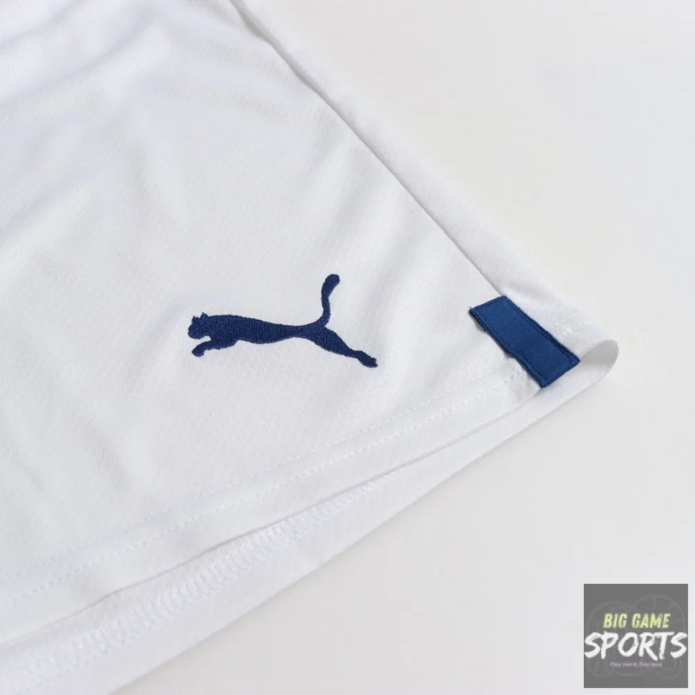 Close-up of a white Puma athletic garment corner with a navy blue Puma logo and a matching navy fabric tab, photographed on a clean white background.
