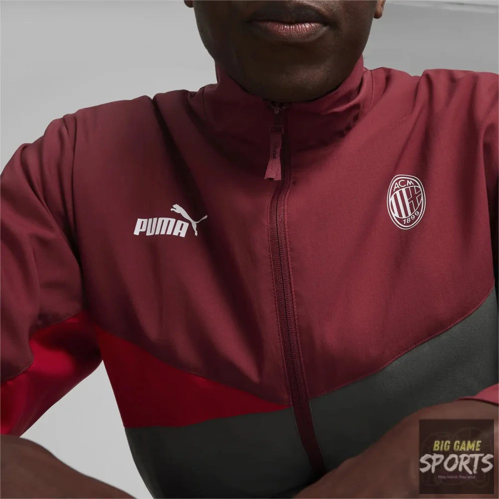 A close-up of a person wearing a Puma AC Milan track jacket. The jacket is maroon with a dark gray colorblock at the bottom and features the white Puma logo on the right chest and the AC Milan crest on the left chest.