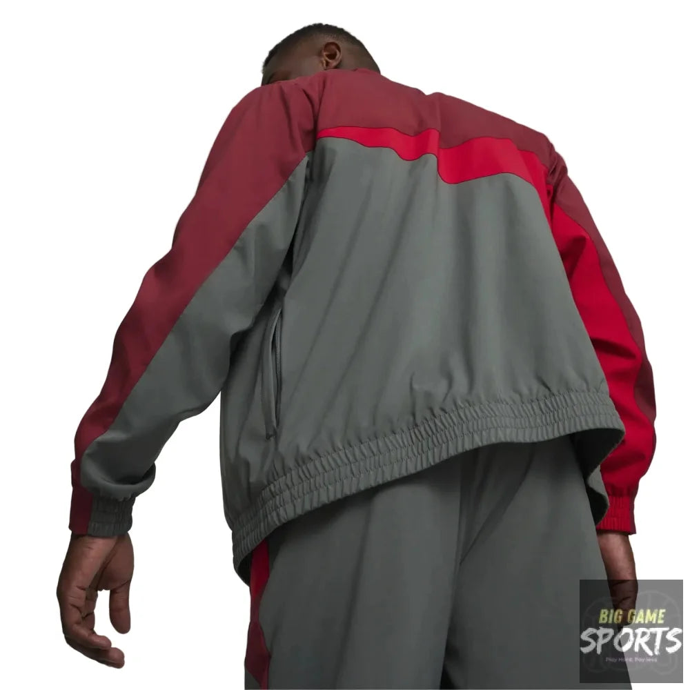 A person shown from behind wearing a color-blocked jacket with a gray body, red shoulder and sleeve panels, and matching gray pants against a light gray studio background.