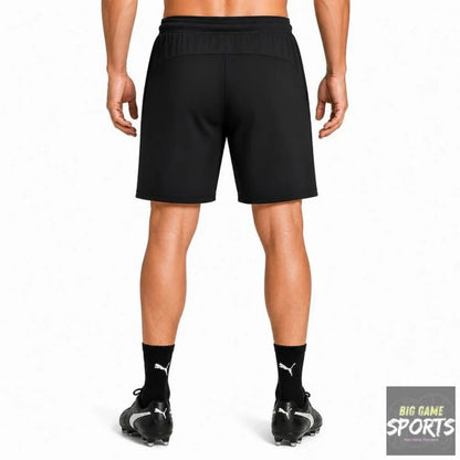 Black athletic shorts shown from the back on a model, paired with black Puma socks and Puma cleats against a plain white background.