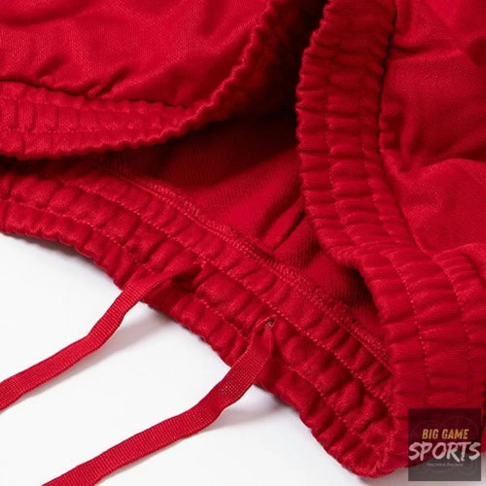 Close-up of a bright red textured fabric garment, showing gathered ruffled trim and matching drawstrings on a white background.