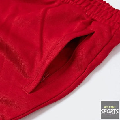 Close-up of a bright red athletic shorts fabric showing a side pocket and elastic waistband on a white background.