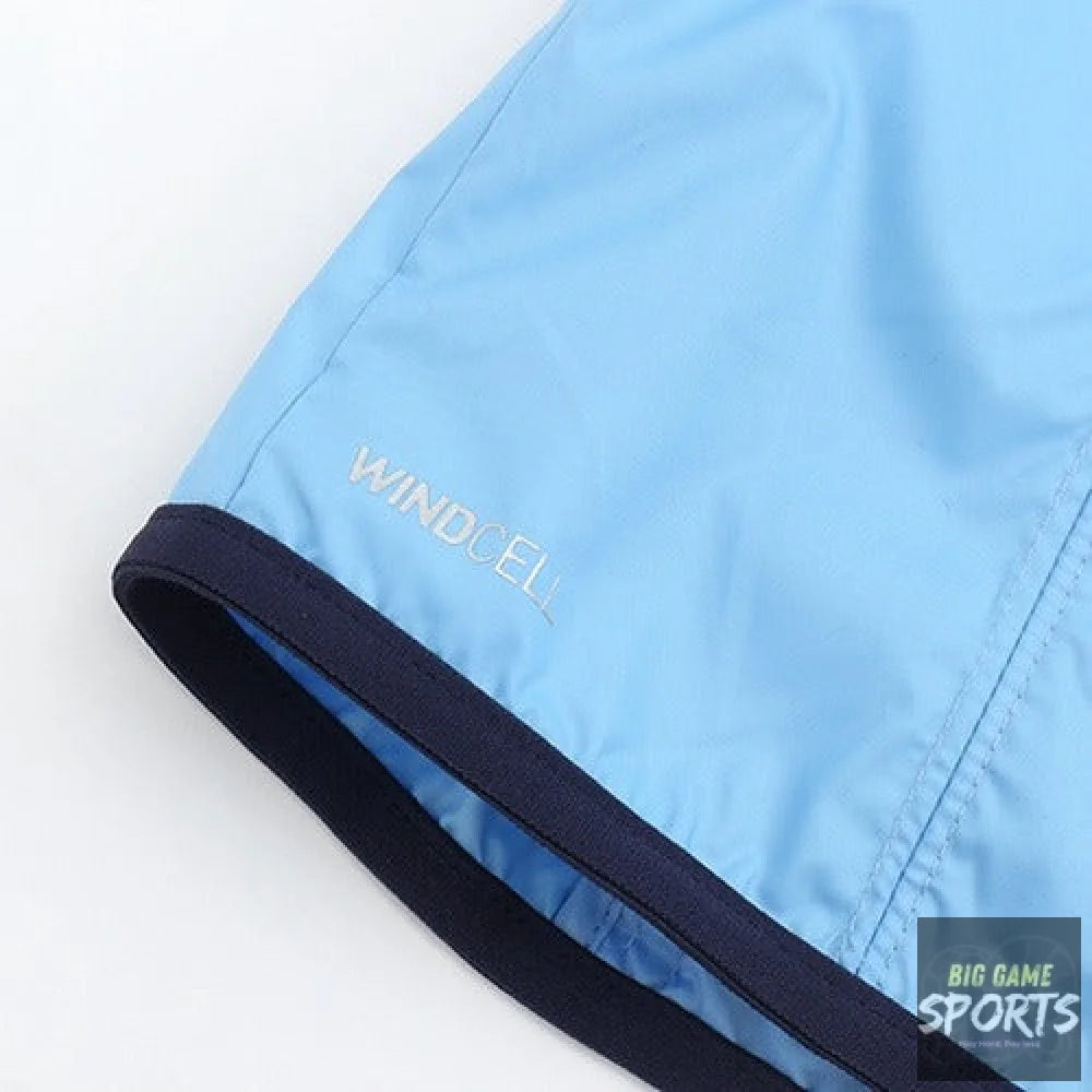 Close-up of a light blue athletic jacket or windbreaker sleeve with a dark navy ribbed trim and the word 'WINDCELL' printed in light gray near the cuff.