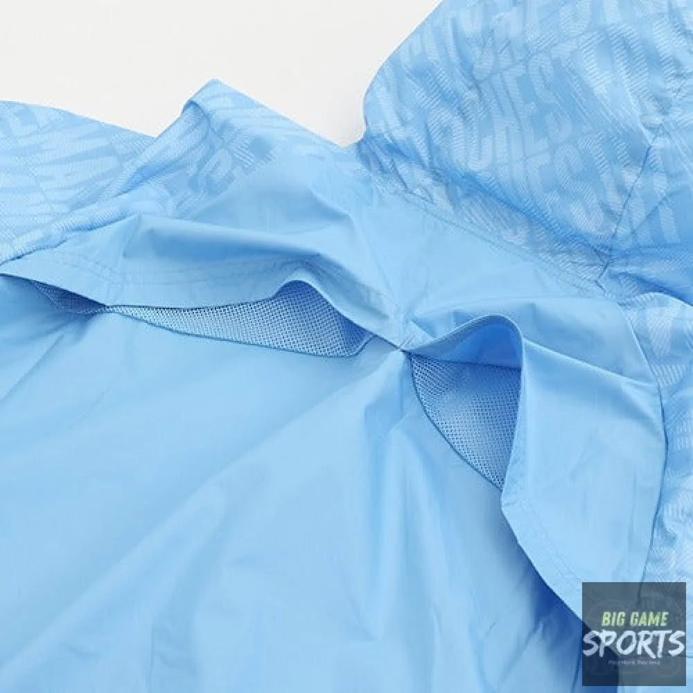 Close-up of a light blue lightweight jacket or windbreaker, showing the fabric texture, mesh lining, and a subtle tonal pattern on the sleeve.