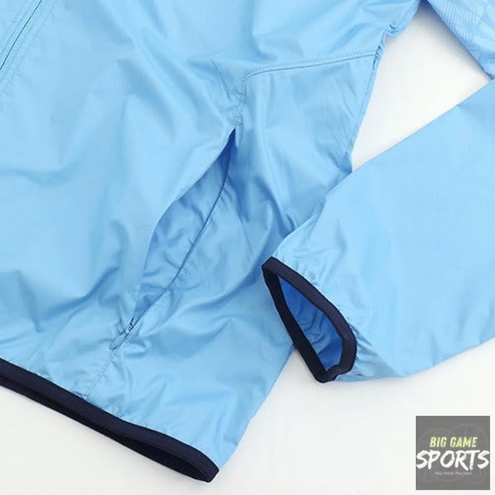 A close-up of a light blue lightweight jacket or windbreaker, showing the fabric texture, zipper, and dark navy trim on the sleeve cuff and hem.