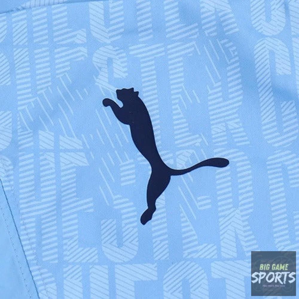 A close-up of a light blue Puma garment featuring the dark navy Puma leaping cat logo centered over a tonal geometric pattern.