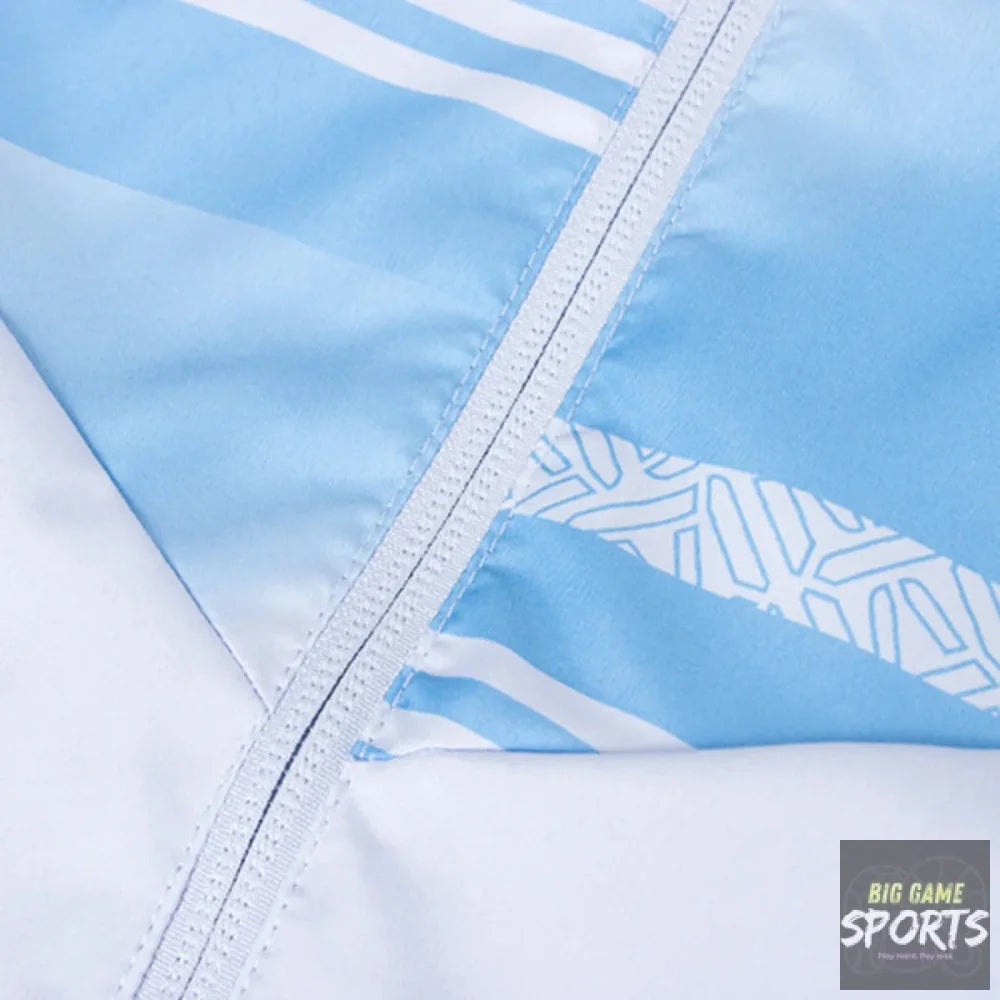 Close-up of a light blue and white garment, showing a diagonal white zipper, white stripes, and a geometric patterned section.