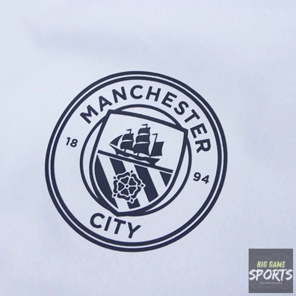 Close-up of a Manchester City crest printed in dark navy on a white fabric surface.