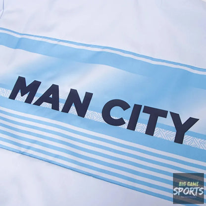 A close-up of a white garment featuring light blue horizontal stripes and the text 'MAN CITY' printed in dark navy across the chest.
