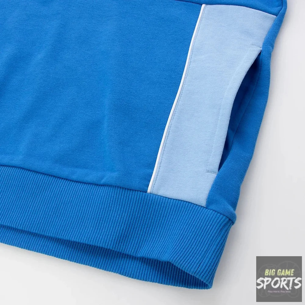 Close-up of a blue ribbed knit garment, likely a sweatshirt or jacket sleeve, featuring a light blue vertical stripe panel and a white piping accent on a white background.