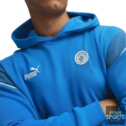 Person wearing a blue hoodie with Puma logo and Manchester City badge.