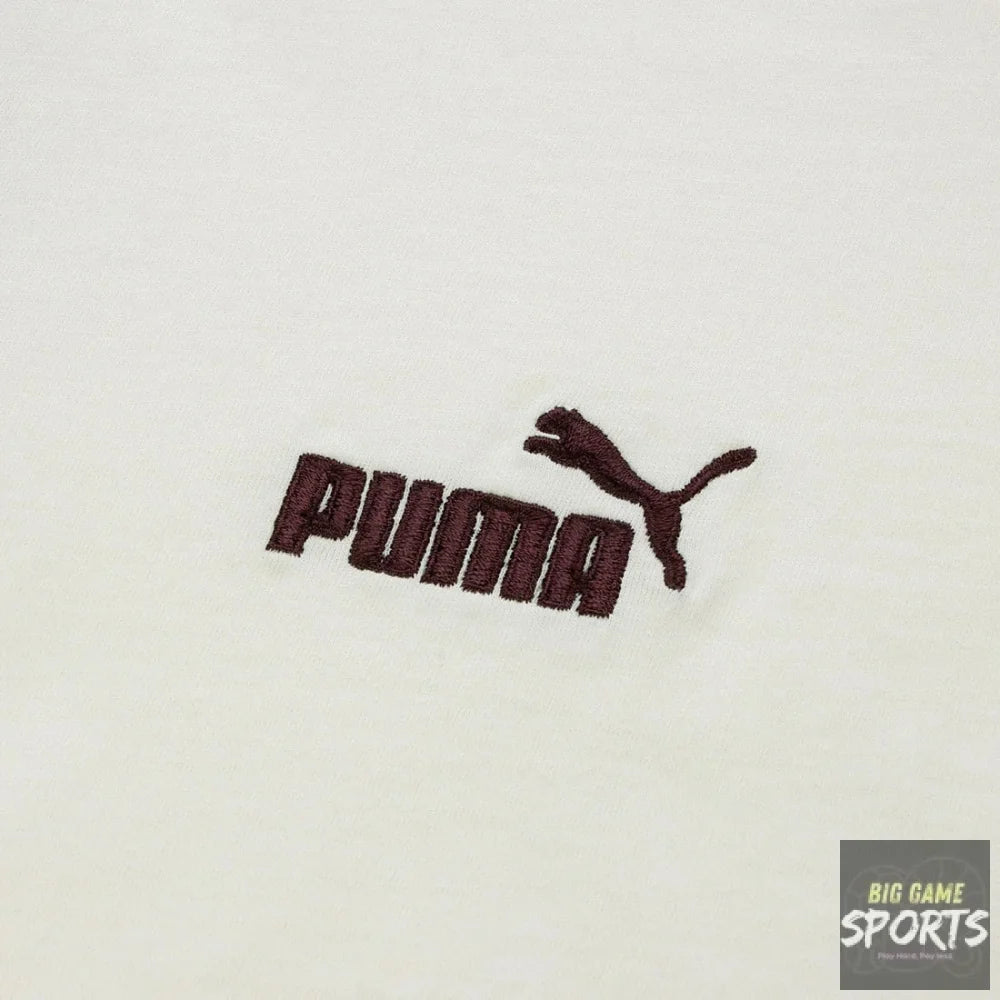 A close-up of a white fabric surface featuring an embroidered dark brown Puma logo and leaping cat emblem.