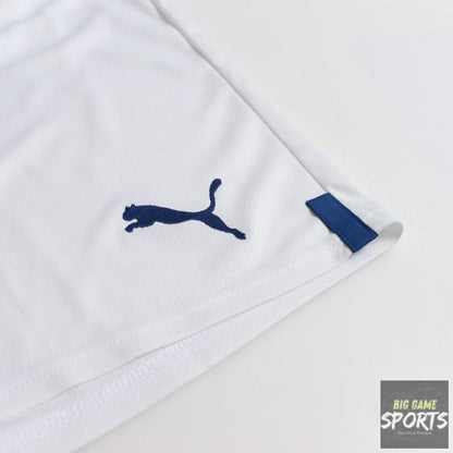 Close-up of a white Puma athletic garment corner with a navy blue Puma logo and a matching navy fabric tab, photographed on a clean white background.